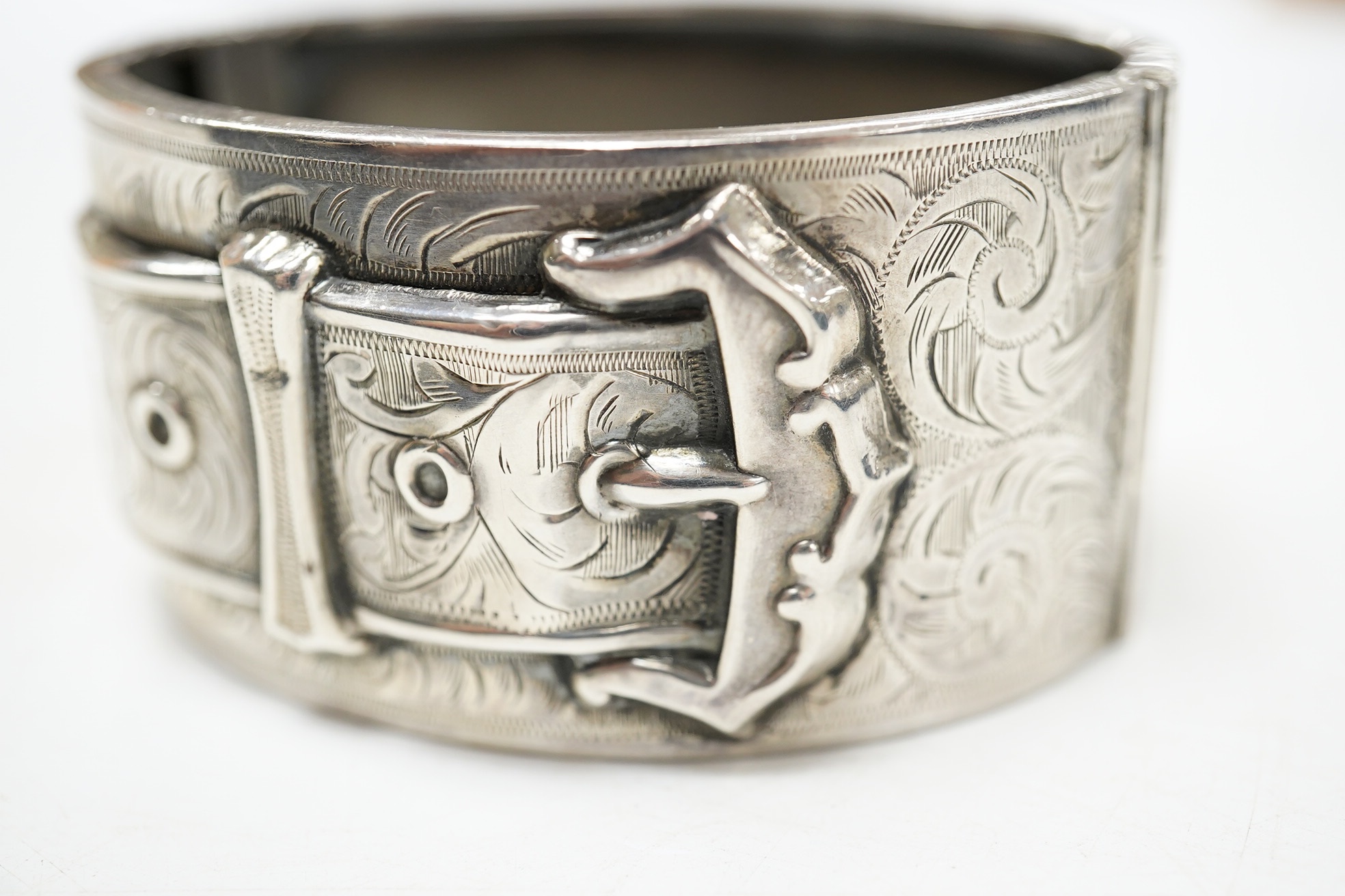 A George V engraved silver hinged bangle, with 'buckle' decoration, Kirwan & Co Ltd, Birmingham, 1913. Condition - poor to fair